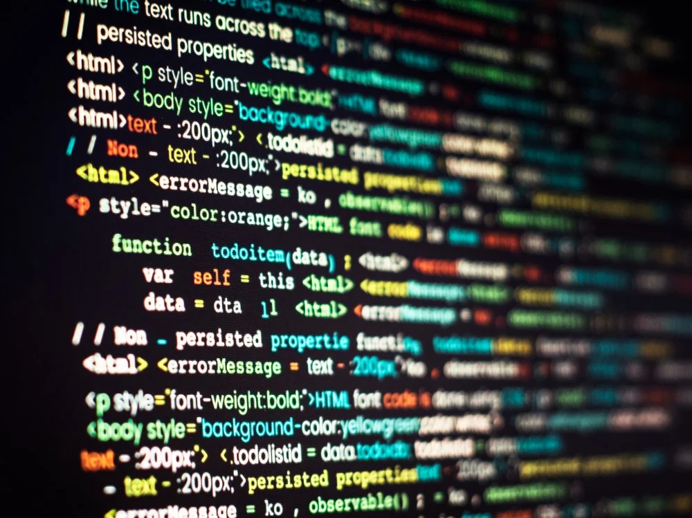 Színes forráskód sorok fekete monitor kijelzőjén közelről fotózva.